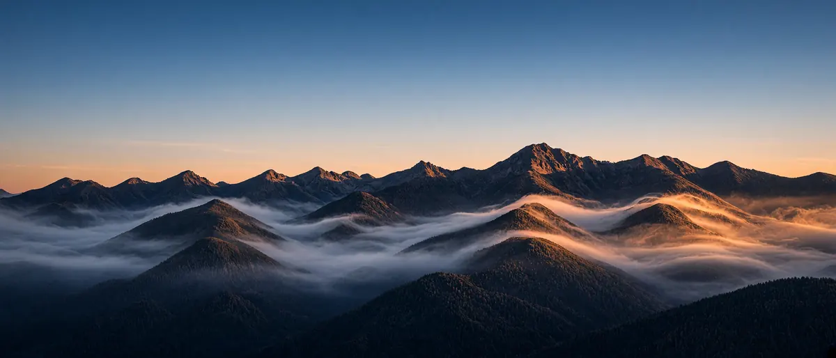 Layered mountain ridges at sunrise with mist in the valleys